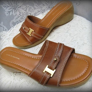 May include: A pair of brown leather heeled sandals with a gold buckle. The sandals have a stitched design and the brand name "croft & barrow" is visible on the insole.