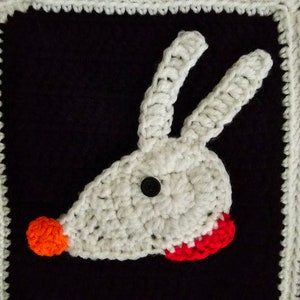 May include: White crocheted animal head with a red nose and red mouth, on a black background with a white crocheted border.