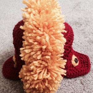 May include: A red crocheted hat with a yellow yarn pom-pom on top.
