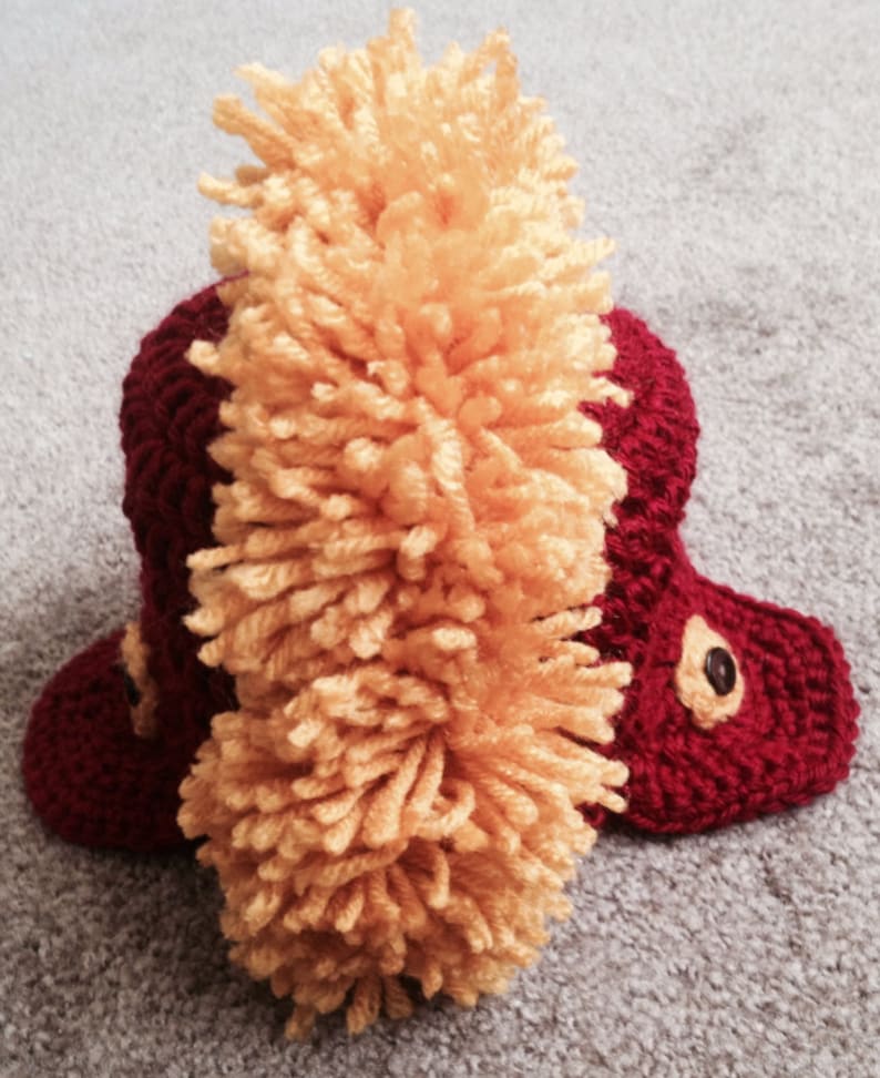 May include: A red crocheted hat with a yellow yarn pom-pom on top.