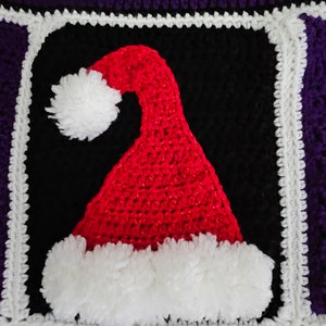 May include: A crocheted square with a red and white Santa hat design. The hat is surrounded by a black square with a white border and a purple border.