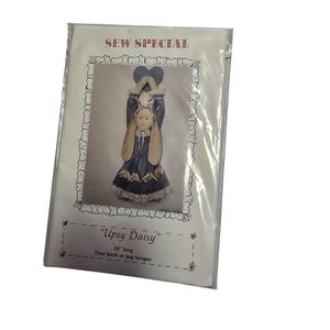 Puede incluir: Patrón de Sew Special para una muñeca "Upsy Daisy", un colgador de pomo de puerta o percha de 74 cm de largo. La muñeca lleva un vestido azul y blanco con una diadema de orejas de conejo marrón y sostiene un corazón rosa.