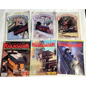 Könnte beinhalten: Eine Sammlung von acht Vintage-Modellbahnmagazinen. Die Titelseiten zeigen farbenfrohe Illustrationen von Zügen, Landschaften und Modellbahnanlagen. Die Magazine heißen "Garden Railways", "Outdoor Railroader" und "Fine Scale Railroader".