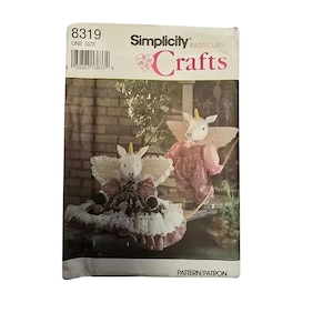 May include: A Simplicity Crafts pattern featuring a unicorn doll. The pattern packet shows a finished doll with a white head, yellow horn, and pink and white dress. The packet has the number 8319 and the words "Simplicity Crafts".