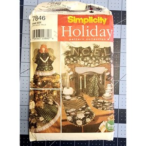 Op de afbeelding: Een Simplicity Holiday patrooncollectie naai-patroon voor een kerstboomtopper, een schouwdecoratie en een tafelloper. Het patroon bevat een groen en wit bloemenontwerp met een witte kantversiering. Het patroonnummer is 7846.