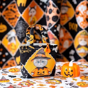 May include: A small black and yellow Halloween trick-or-treat bag with a cat wearing a witch hat and holding a jack-o-lantern. The bag has the word "Halloween" printed on it.