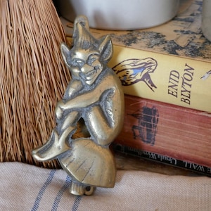 Peut inclure: Une figurine en laiton représentant un gobelin ou un lutin assis sur un champignon. La figurine est détaillée avec une expression espiègle et des oreilles pointues.