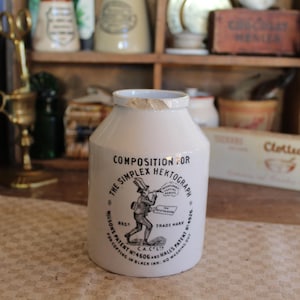 Peut inclure: Pot en céramique blanche avec inscription noire : "Composition for The Simplex Hektograph. Wilson's Patent No. 4600 and Hall's Patent for copying in Black Ink. No washing out."