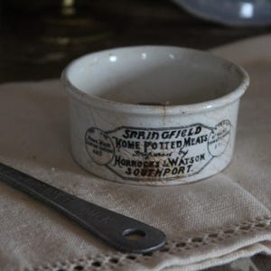 Może przedstawiać: Biały ceramiczny garnek z pokrywką, z napisem "Springfield Home Potted Meats Prepared by Horrocks & Watson Southport".