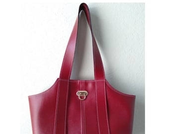 May include: A red leather tote bag with white stitching and a gold clasp. The bag has a structured shape and two top handles.