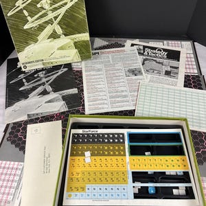 May include: A vintage board game titled "StarForce: Alpha Centauri" with a green box and various game components. The box features futuristic illustrations and text. Includes rule books, game boards, and game pieces.