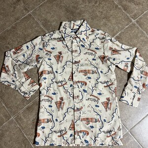 May include: Cream-colored button-down shirt with a repeating pattern of canoes, teepees, and other outdoor elements in shades of brown, blue, and orange. The shirt has long sleeves and a classic collar. The Levi's logo is visible on the collar.