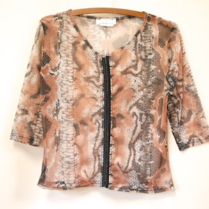 Può includere: Un top in rete con stampa a pelle di serpente marrone e nero con una cerniera nera sul davanti.