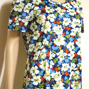 May include: A short-sleeved dress with a round neckline and a floral print. The dress features a blue background with white, red, and green flowers.