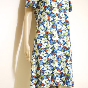 May include: A short-sleeved dress with a floral print in shades of blue, white, orange, and green. The dress has a round neckline and a slightly flared skirt.