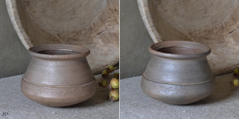 Może przedstawiać: Mały, okrągły, brązowy ceramiczny garnek z szerokim, rozszerzanym brzegiem i gładką, lekko teksturowaną powierzchnią. Garnek posiada subtelny poziomy pasek wok&oacute;ł środka korpusu. Przedmiot jest oznaczony kodem J51 w rogu zdjęcia.
