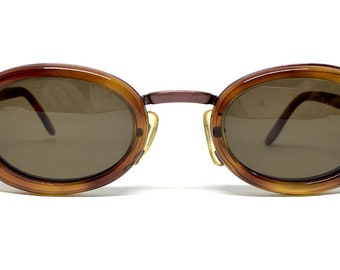 May include: Brown tortoise shell oval sunglasses with brown lenses and a thin metal bridge.