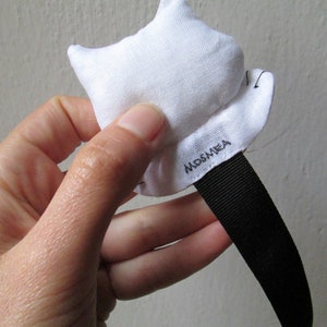 Peut inclure: &Eacute;toile en tissu blanc avec une sangle noire et le mot "MOSMEA" brod&eacute; dessus.