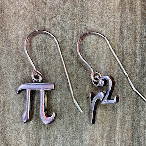 May include: A pair of silver earrings with a mathematical symbol charm. One earring features the symbol for pi, and the other earring features the symbol for the square root of 2.