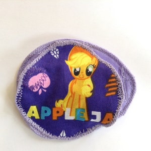 May include: Purple fabric reusable makeup remover pads with a cartoon image of a yellow pony with a pink heart and the text "APPLEJA" in rainbow colors.