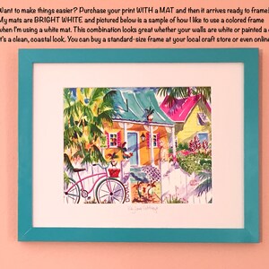 May include: A watercolor painting of a colorful house with a green roof and a white picket fence. The house is surrounded by lush greenery and flowers. A pink bicycle is parked in front of the house. The painting is framed in a teal frame.