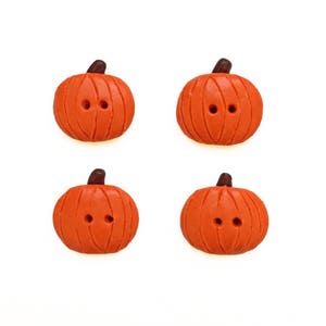 May include: Four orange pumpkin-shaped buttons with brown stems and two black eyes each.