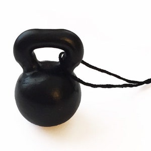 Puede incluir: Un adorno de kettlebell negro con una cuerda negra.