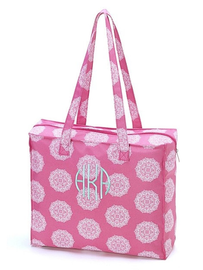 Puede incluir: Una bolsa de mano rosa con dise&ntilde;os de mandalas blancas y un monograma "AKA" en azul claro. La bolsa tiene dos asas superiores y un cierre de cremallera.