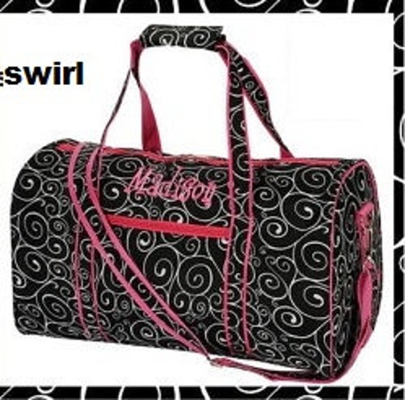 May include: Black and pink travel duffel bag with a swirl pattern and the word "Maddie" embroidered on the front.