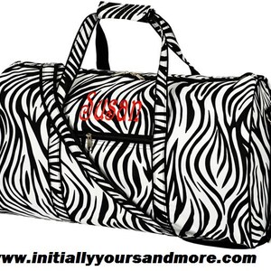 May include: Black and white zebra print duffel bag with a zipper closure and a red embroidered name "Susan".