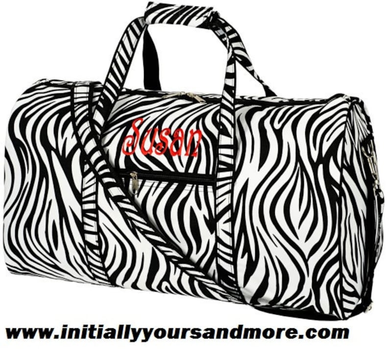 May include: Black and white zebra print duffel bag with a zipper closure and a red embroidered name "Susan".