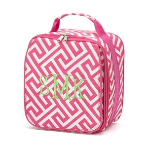 May include: Pink and white geometric patterned lunch bag with a zipper closure and a green embroidered monogram "SMK".