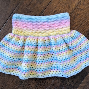 May include: A pastel rainbow crochet skirt with a ruffled hem. The skirt is made with a soft, lightweight yarn and is perfect for a baby or toddler.