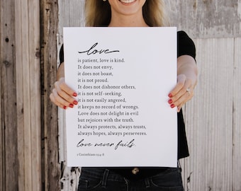 May include: A white poster with black text that reads "love is patient, love is kind. It does not envy, it does not boast, it is not proud. It does not dishonor others, it is not self-seeking, it is not easily angered, it keeps no record of wrongs. Love does not delight in evil but rejoices with the truth. It always protects, always trusts, always hopes, always perseveres. love never fails. 1 Corinthians 13:4-8"