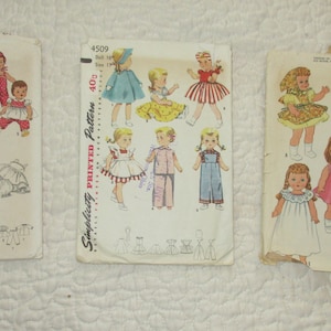 May include: Three vintage sewing patterns for making doll clothes. The patterns are Simplicity 3669, Simplicity 4509, and McCall's 2466. The patterns feature illustrations of dolls wearing different outfits.