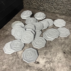 Puede incluir: Un conjunto de fichas octogonales de color gris claro, cada una con las letras "SP" en relieve. Las fichas están dispersas sobre una superficie gris texturizada. Cada ficha tiene un borde en relieve y un diseño en hueco.