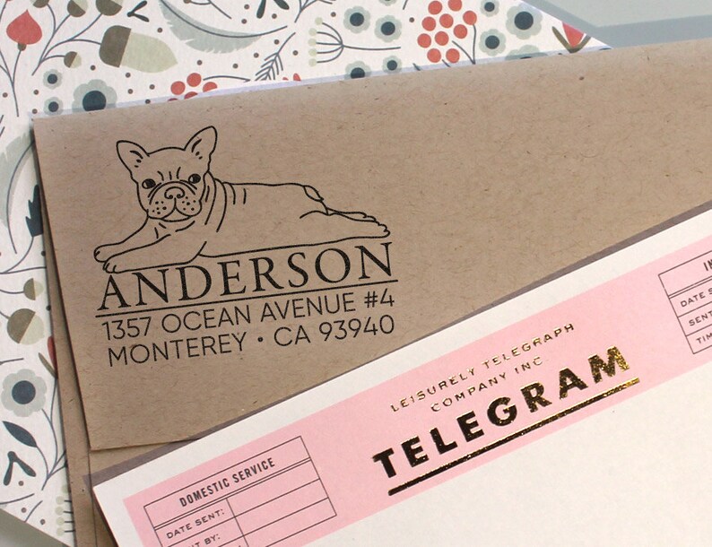 K&ouml;nnte beinhalten: Ein brauner Papierumschlag mit einer Schwarzwei&szlig;illustration eines franz&ouml;sischen Bulldoggen. Der Umschlag hat ein R&uuml;cksendeetikett mit dem Text "ANDERSON 1357 OCEAN AVENUE #4 MONTEREY &bull; CA 93940".
