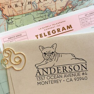K&ouml;nnte beinhalten: Ein brauner Umschlag mit einer goldenen B&uuml;roklammer und einem schwarzen und wei&szlig;en Stempel eines franz&ouml;sischen Bulldoggen mit dem Text "Anderson 1357 Ocean Avenue #4 Monterey CA 93940".