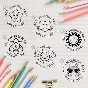 May include: Six circular black ink stamps on lined paper. Designs include a star, heart, sun, atom, and smiley face with a bucket hat. Each stamp features text such as Mrs. Maggio Says Great Job or Mr. Anderson Says Great Job. Colored pencils surround the stamps.
