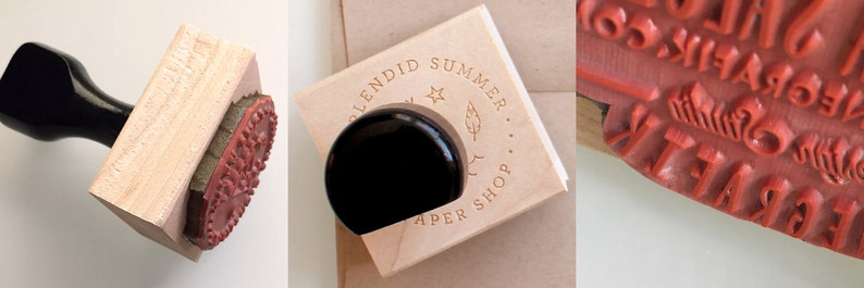 May include: A wooden stamp with a black handle. The stamp features the text "Splendid Summer Paper Shop" with a star and a feather design. The stamp is mounted on a wooden block.