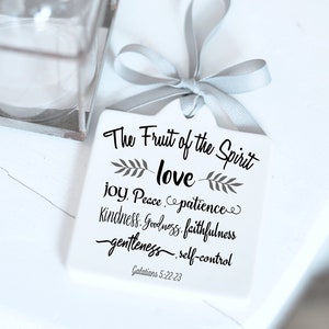 May include: A white, square gift tag with a gray ribbon, featuring the text "The Fruit of the Spirit: love, joy, peace, patience, kindness, goodness, faithfulness, gentleness, self-control" and Galatians 5:22-23. The tag has a customizable message on the back.