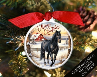 May include: A round white Christmas ornament with a black horse walking through a snowy winter scene. The ornament has a red ribbon and the text "Merry Christmas" on the front.