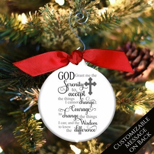 May include: White round Christmas ornament with a red ribbon. The ornament features a black and white graphic with the text "GOD Grant me the Serenity to accept the things I cannot change; Courage to change the things I can; and the Wisdom to know the difference". A gray cross is included in the graphic. The ornament has a customizable message on the back.