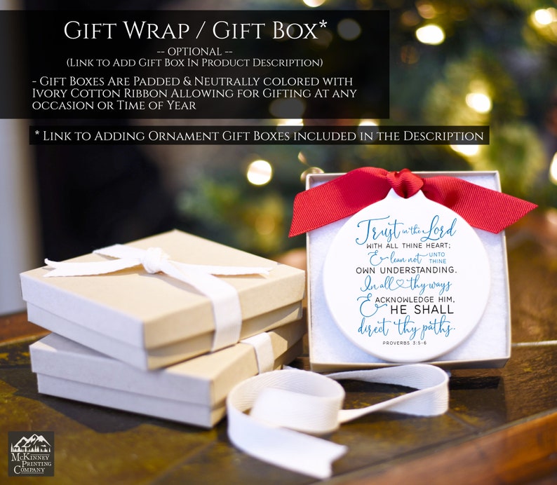 May include: A white ornament with a red ribbon, featuring the text "Trust in the Lord." The ornament is in a gift box with a white ribbon. Additional gift boxes are stacked nearby, tied with ivory ribbons. Text at the top reads "Gift Wrap / Gift Box."
