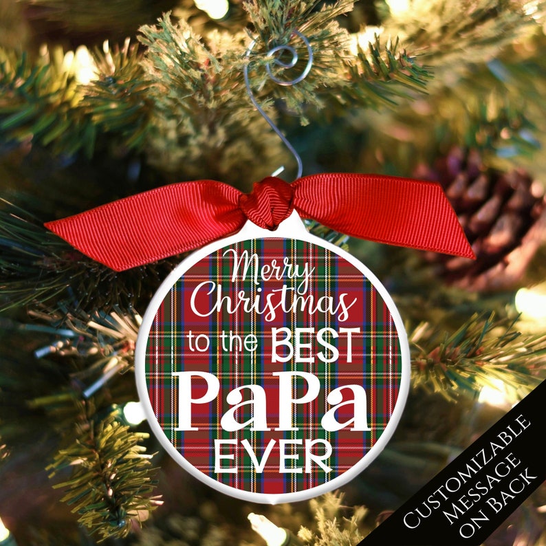 May include: Red and green plaid Christmas ornament with white text that reads "Merry Christmas to the Best Papa Ever".