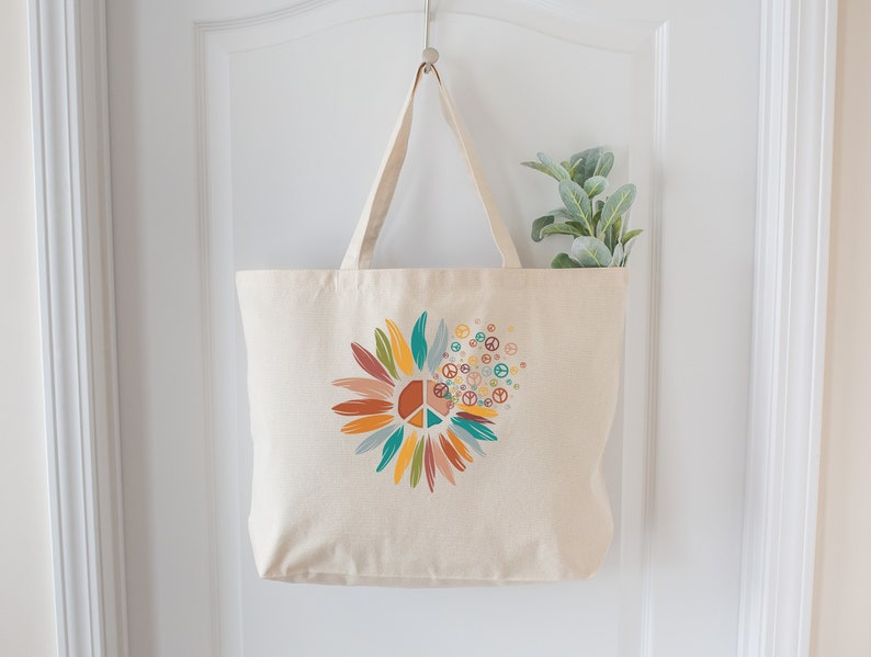 May include: A beige canvas tote bag with a colorful peace sign sunflower design. The sunflower is made up of peace signs and has a variety of colors including orange, yellow, green, blue, and red.