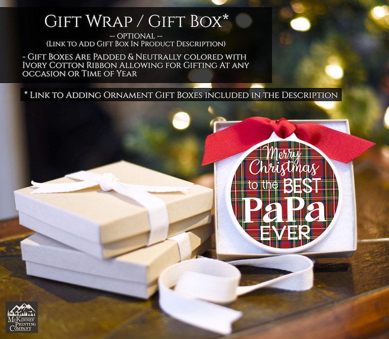 May include: A white ceramic ornament with a red and green plaid pattern and the text "Merry Christmas to the Best Papa Ever". The ornament is in a white gift box with a red ribbon.