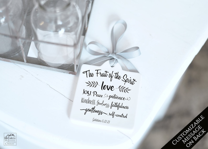 May include: A white, square gift tag with a gray ribbon, featuring the text "The Fruit of the Spirit: love, joy, peace, patience, kindness, goodness, faithfulness, gentleness, self-control" and Galatians 5:22-23. The tag has a customizable message on the back.