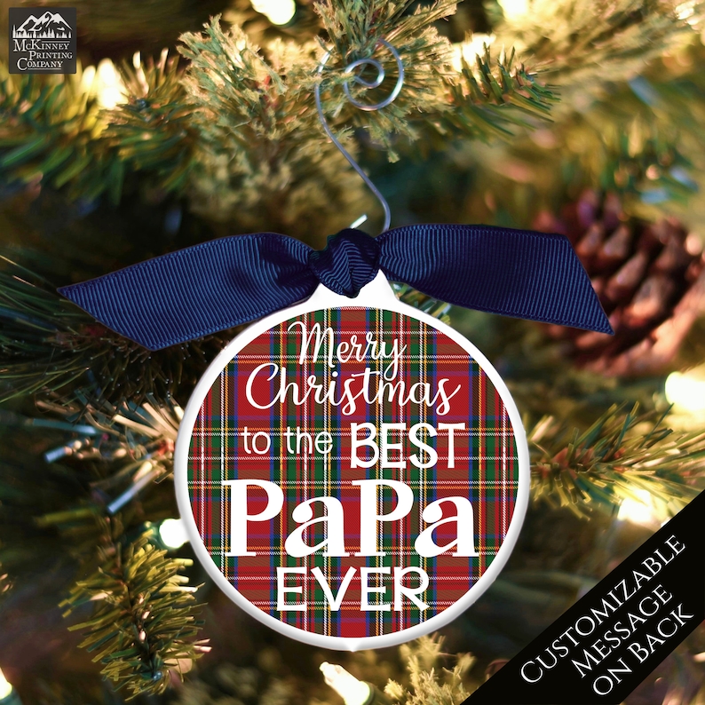 May include: Red and green plaid Christmas ornament with white text that reads "Merry Christmas to the Best Papa Ever".