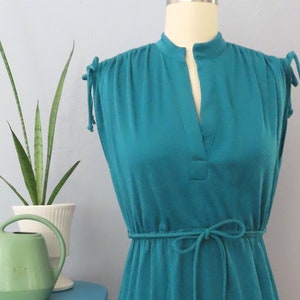 May include: Teal sleeveless dress with a V-neck and a tie at the waist.